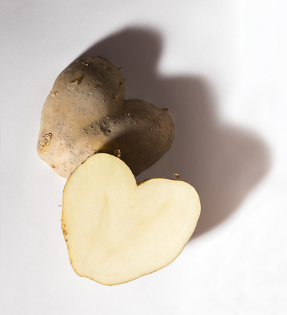 Heart shaped potato cut in half, on a white background.の写真素材
