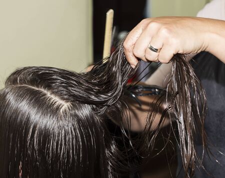Hand is brushing wet hair, before cutting them with scissors.の写真素材