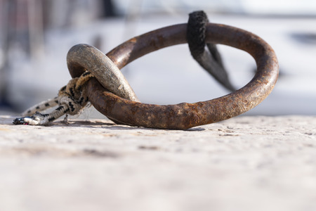 Metal ring in a dock with attached rope holding a boat.