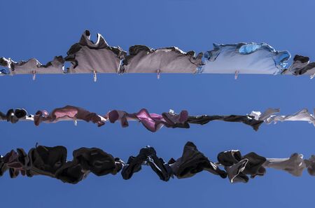 Hanging washed clothes on ropes in mid day sun.の写真素材