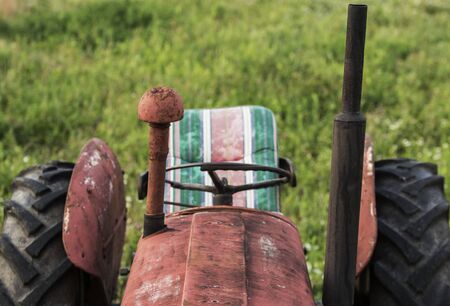 Red old tractor front part with seat.