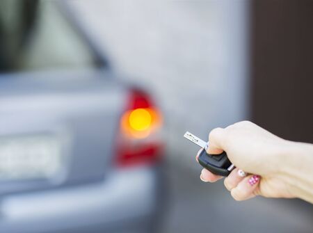 Hand locking the car with a key.