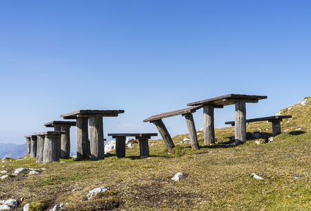 Wooden benches on top of a hill with a clear sky and mountain view.の写真素材