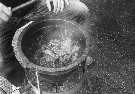Person is cooking some goulash in a big metal pan with gas heater.
