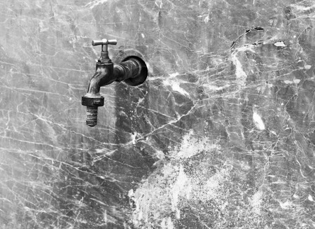 Closed water faucet on a marble wall withの写真素材