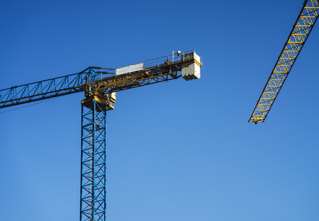 Two construction cranes with a clear sky behind of them.の写真素材