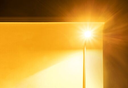 Street lamp infront of a yellow house with a bright beam.の写真素材