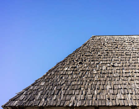 Old decayed wooden roof made of shingles with a clear background.