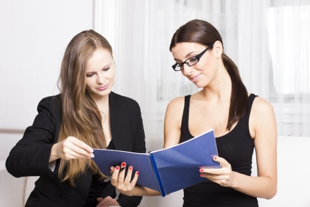 Two beautiful businesswomen with document having discussionの写真素材