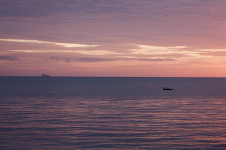 An islander paddles a dug out canoe in Thailand at sunsetの写真素材