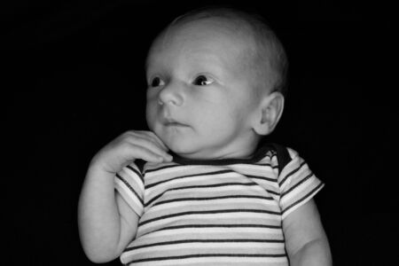 A 3 Week Old Baby Poses on a Black Background. Perfect for Memes with Copy Space.の写真素材