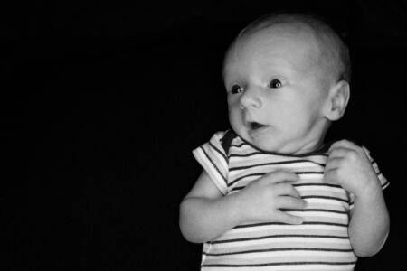 A 3 Week Old Baby Poses on a Black Background. Perfect for Memes with Copy Space.の写真素材