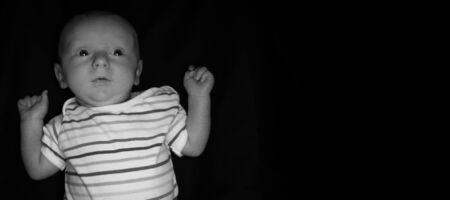 A 2 Month Old Baby Poses on a Black Background. Perfect for Memes with Copy Space.