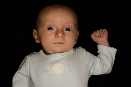 A Three Month Old Baby Poses on a Black Background. Perfect for Memes with Copy Space.の写真素材