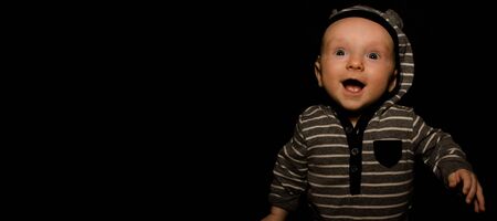 A 4 Month Old Baby Poses on a Black Background. Perfect for Memes with Copy Space.の写真素材