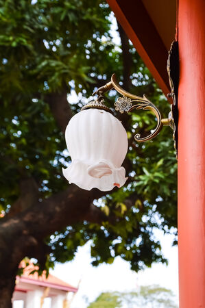 Outdoor lamp attached on the red pole with blurry backgroundの写真素材