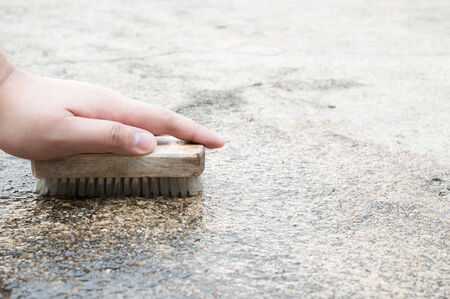 Cleaning an outdoor floor in a house area by brushing with a brush