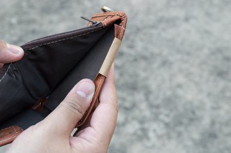 Broke man showing his brown leather wallet with no money on a poor economy day