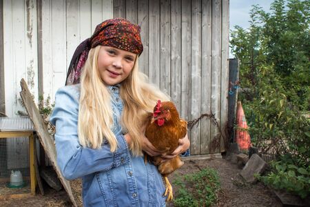 Girl holding a brown chicken in her armsの写真素材