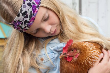Girl with brown chicken in her armsの写真素材
