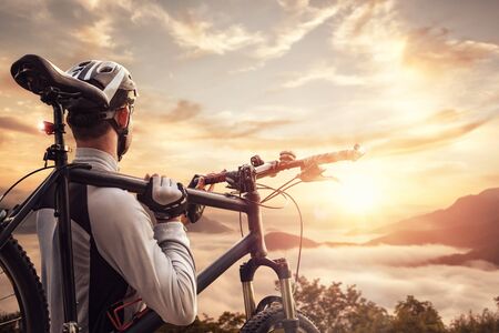 Mountain biker overlooking a valley at sunsetの写真素材