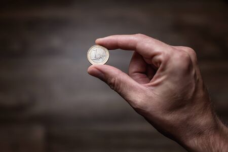 Euro coin in between thump and index finger