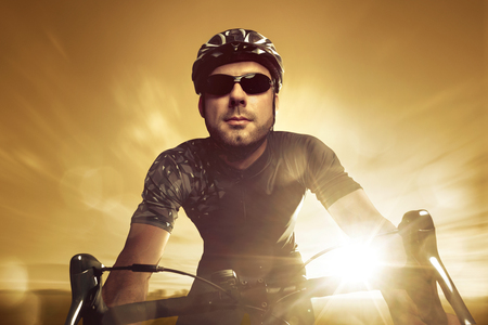 Front view of a racing cyclist during sunsetの写真素材