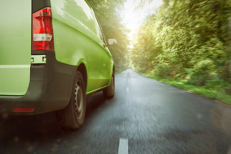 Green delivery van driving through the forestの写真素材