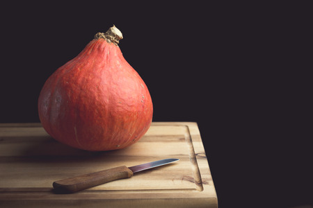 Pumpkin and knife on a wooden cutting boardの写真素材