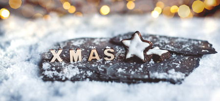 Christmas decoration with gingerbread stars and wooden XMAS letters in the snowの写真素材