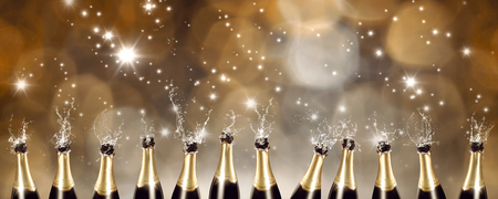 Splashing Champagne bottles with blurred lights in the backgroundの写真素材