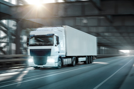 Truck driving on a road through an industrial style bridgeの写真素材