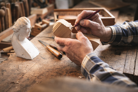Experienced hands of an artisan sketching the outlines of a sculpture with a pencilの写真素材