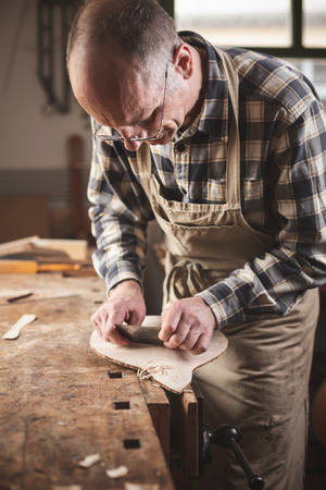 Experienced instrument builder at work in a rustic workshopの写真素材