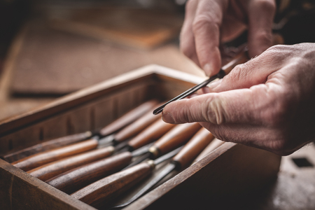 Mature hands holding a carving toolの写真素材