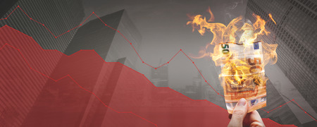 Falling stock prices ?? burning 50? ? banknote in front of a declining graphの写真素材