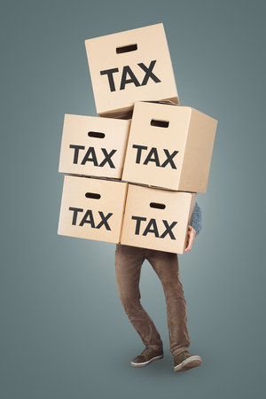 A person carrying a large stack of document storage boxes labeled with ? ?? TAXの写真素材
