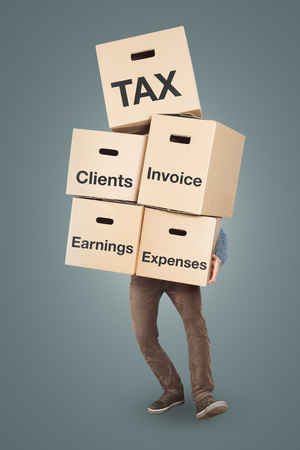 Accountant carrying a large stack of cardboard boxes labeled with: tax, clients, invoice, earnings, expensesの写真素材
