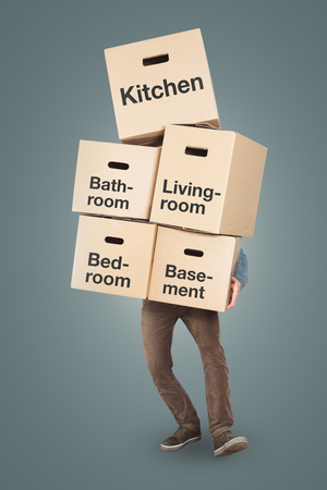 Man carrying a big stack of moving boxes labeled with different roomsの写真素材