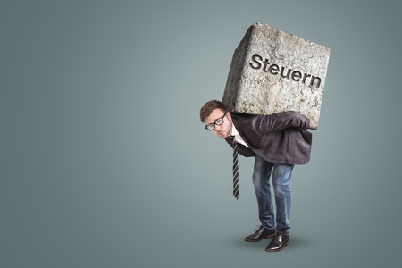 Businessman carrying a heavy stone with the german word ? ? ?steering? ?? printed on it - conceptの写真素材