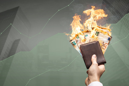 Cash flow is on fire - high financial gains concept with burning banknotes and a rising graphの写真素材