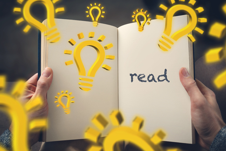 Education concept - hand-held book with 3d lightbulb symbols and the word ? ?? read? ?? on one pageの写真素材