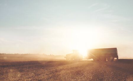Tractor with a trailer on a field during harvestの写真素材