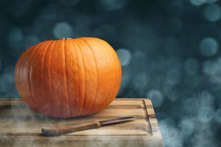 Orange pumpkin and a knife on a wooden board? preparation for Halloweenの写真素材