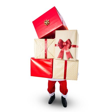 Santa Claus carrying a big stack of Christmas presents - isolated on whiteの写真素材
