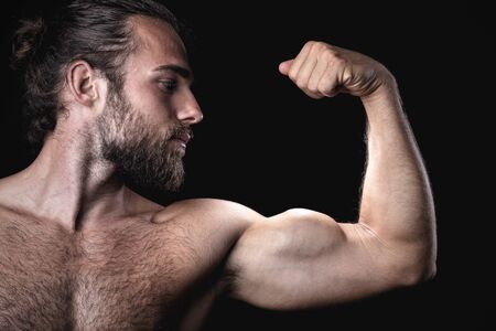 Muscular man with a beard doing a biceps poseの写真素材