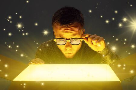 Astonished man looking inside a glowing parcelの写真素材