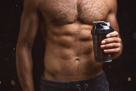 Shirtless torso of a muscular man with a shaker in one handの写真素材