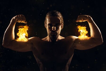 Shirtless man posing with biceps on fireの写真素材