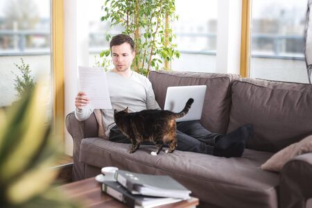 Man at home doing paperwork on the sofaの写真素材